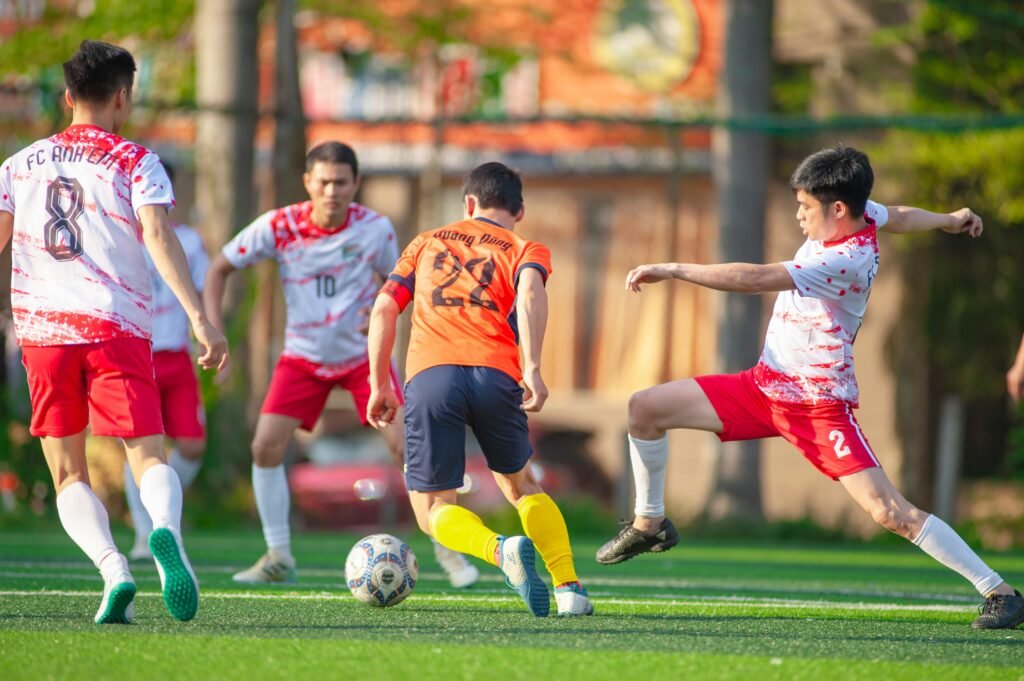 Dynamic football match among young athletes on a sunny day in Hanoi, Vietnam.