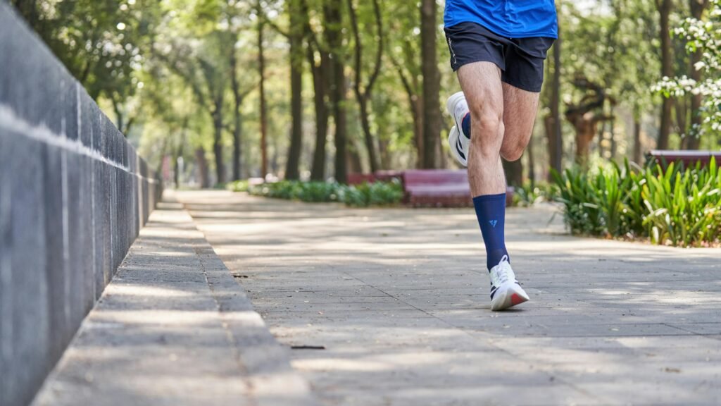 Athlete jogging in park on sunny day, emphasizing fitness and healthy lifestyle.