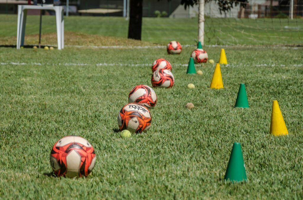 Soccer training equipment arranged on grass in Brasília, Brazil, featuring balls and cones.