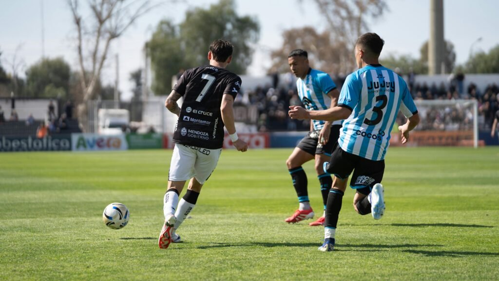 Soccer players in action on the field during a sunny day match.